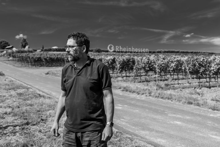 Andreas Huppert steht vor Weinreben von Terra Preta Weingut Rheinhessen